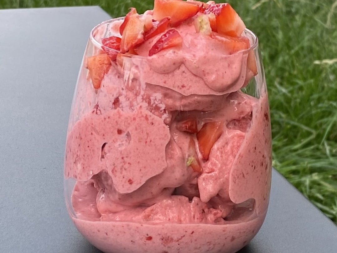 Delicious stawberry ice cream served in glass with added strawberries on top.
